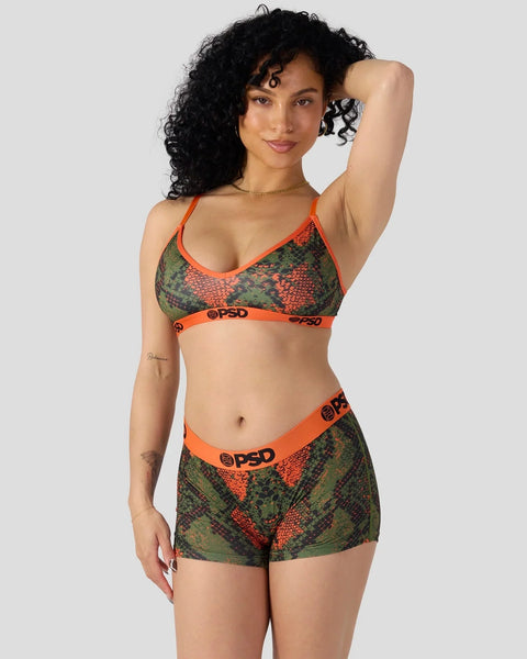 Woman wearing green and red snake-pattern bikini set with orange trim and PSD branding.