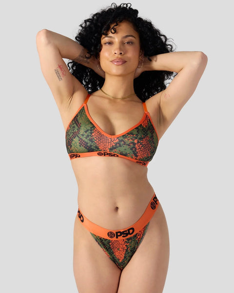 Woman wearing orange and green snake-print bikini set with matching waistband against gray background.