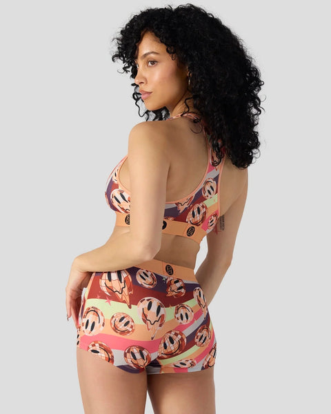 Woman wearing a three-piece set with multicolored striped pattern featuring circular motifs in burgundy, coral, and cream ton