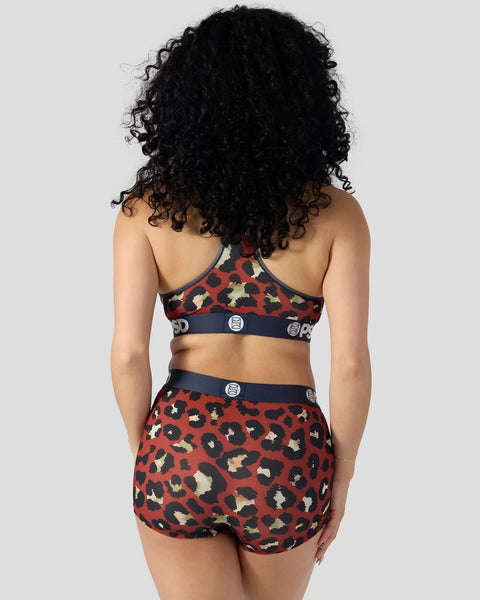 Red leopard print sports bra and shorts set with navy trim and logo details, shown from back view.