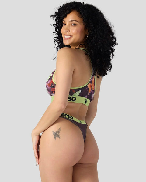 Woman wearing dark floral sports bra and matching briefs with neon green trim and branding.