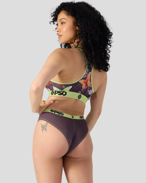 Woman wearing dark purple floral sports bra and briefs with lime green PSD waistbands, shown from back.