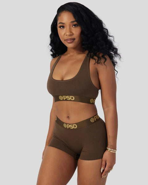 Woman wearing cocoa brown sports bra and shorts set with gold PSD branding.