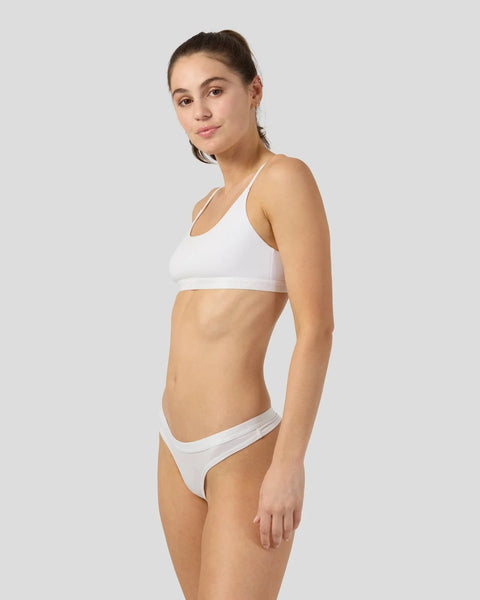 Woman wearing white halter bikini top and matching bottom against neutral background.