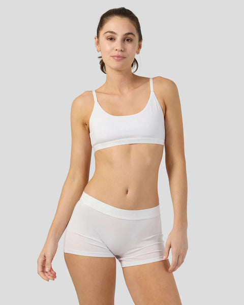 Woman wearing white modal sports bra with matching white shorts against neutral background.
