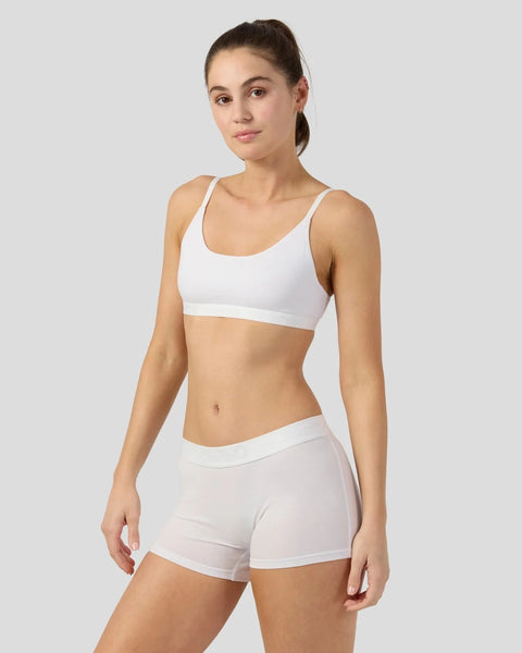 Woman wearing white modal sports bra and matching shorts against neutral background.