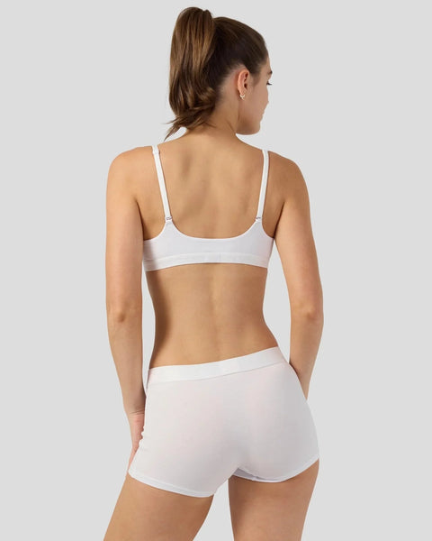 Woman wearing white bra and shorts set, viewed from back.