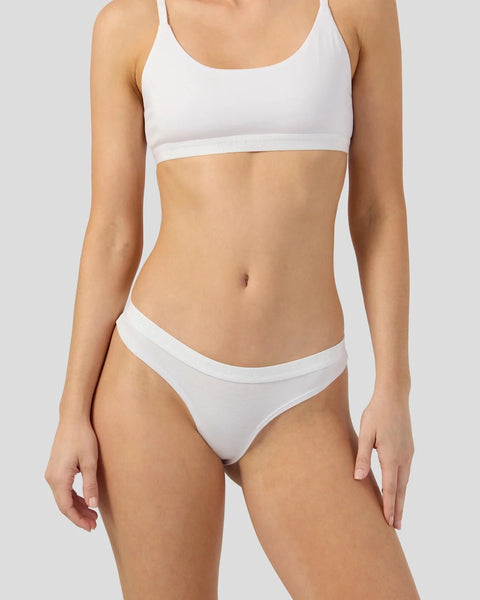 White modal sports bra and bikini briefs on model against neutral background.