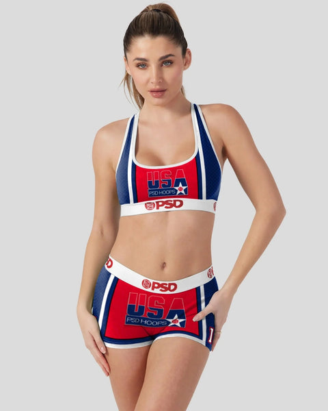 Woman wearing red, white, and navy USA basketball-inspired sports bra and shorts set with PSD branding.