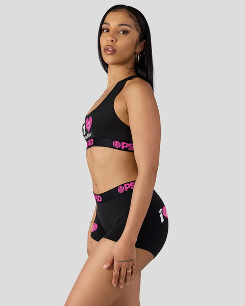 Black sports bra and shorts set with pink heart logo and text branding.