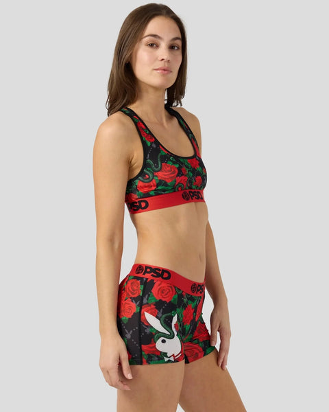 Woman wearing black sports bra and shorts with red rose and snake pattern, red waistband with logo.