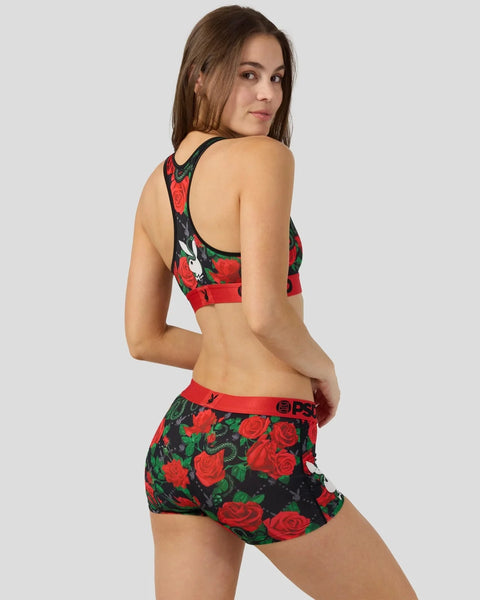 Woman wearing black racerback sports bra and matching shorts with red rose and green leaf print.