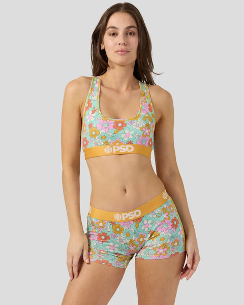 Woman wearing colorful floral print sports bra and matching shorts with orange waistbands.