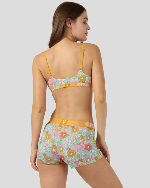 Woman wearing a two-piece set with colorful floral pattern, yellow straps and waistband with logo detailing.
