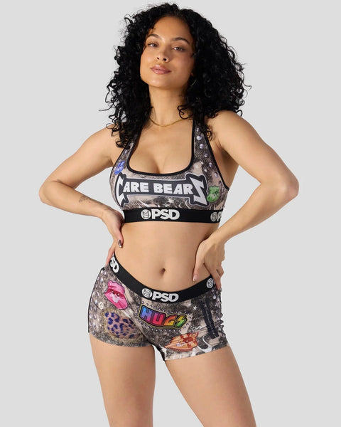 Woman wearing Care Bears graphic sports bra and matching shorts with PSD branding and colorful character prints.
