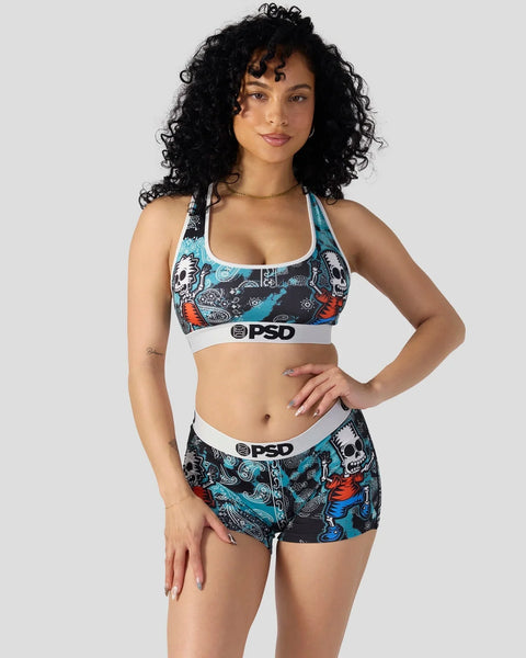 Woman wearing PSD sports bra and shorts with skull and character print design in black, blue, and red.
