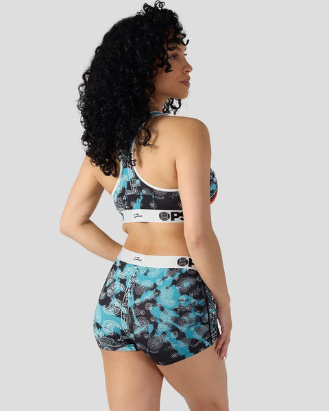Woman wearing blue and black patterned sports bra and shorts set with white elastic bands.