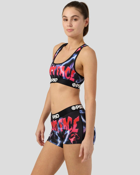 Woman wearing black sports bra and shorts with red and blue graphic print and PSD branding.