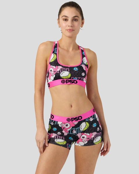 Woman wearing pink and black Gizmo-patterned sports bra and shorts set with neon accents.