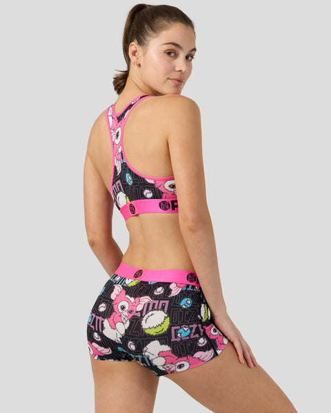 Woman wearing a two-piece athletic set with neon pink trim and black fabric printed with Gizmo character graphics.