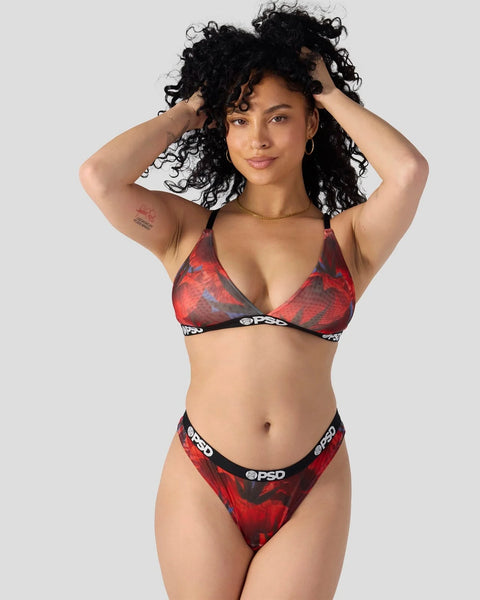 Woman wearing red and black patterned bikini set with PSD branding and halter-style top.