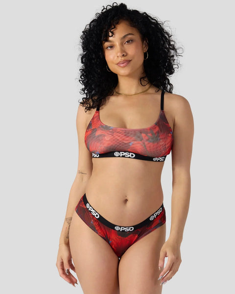 Woman wearing red and black tie-dye sports bra and matching briefs with PSD branding and elastic waistbands.