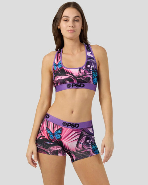 Woman wearing purple and pink sports bra and shorts with butterfly and portrait graphics and PSD branding.