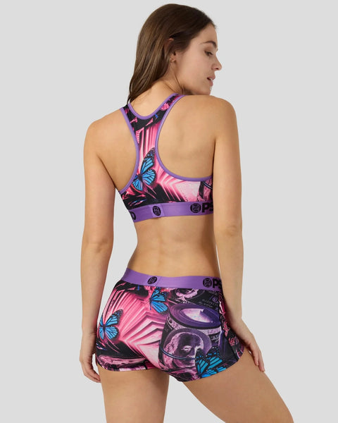 Woman wearing purple-trimmed sports bra and matching shorts with pink, blue butterfly and money print pattern.
