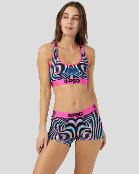 Woman wearing a pink and black holographic patterned sports bra and shorts set with PSD branding.