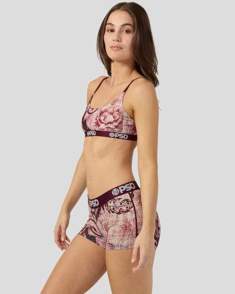 Woman wearing burgundy and pink jacquard floral sports bra and matching shorts with PSD branding.