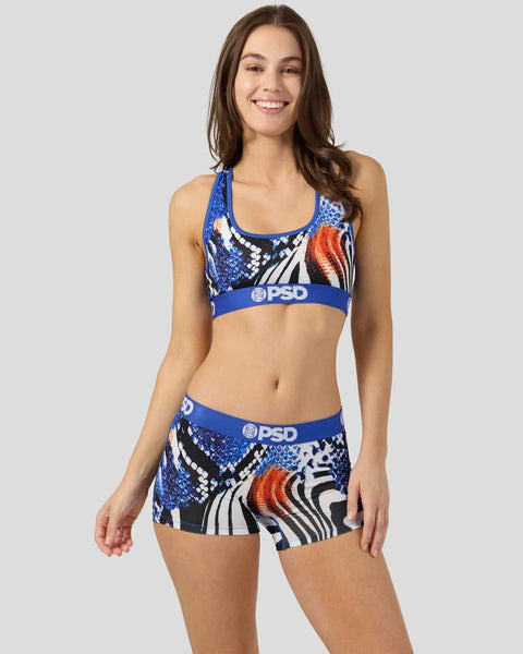 Woman wearing blue, black, white and orange patterned sports bra and shorts set with PSD branding.