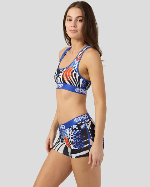 Woman wearing blue, black, white and orange patterned sports bra and shorts set with snake graphic design.