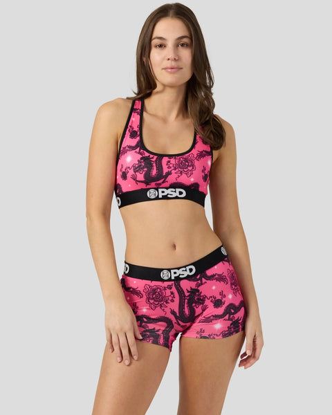 Woman wearing hot pink sports bra and shorts with black airbrushed dragon design and PSD branding.