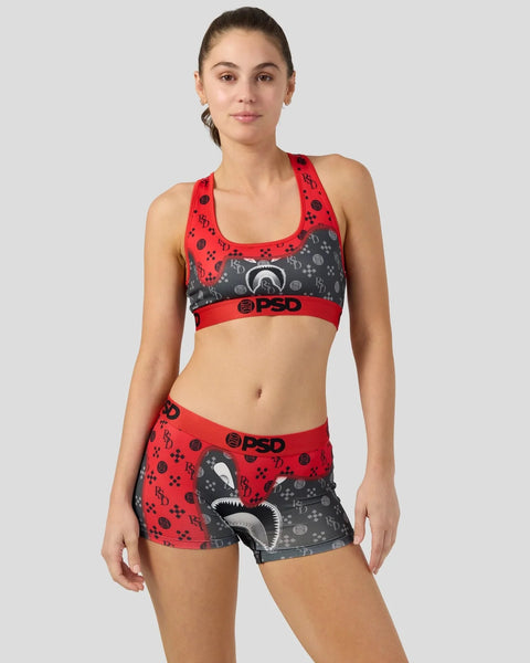 Woman wearing red and gray sports bra and matching shorts with shark graphic print and PSD branding.