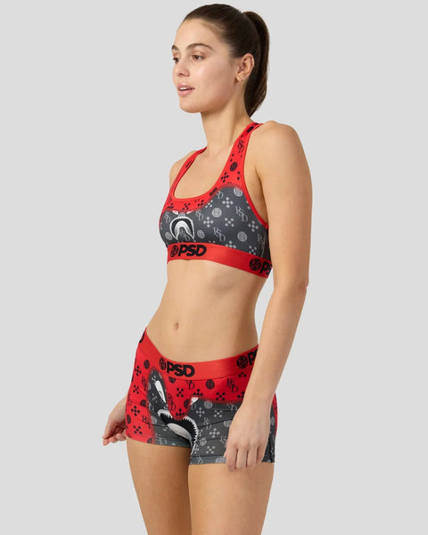 Woman wearing red and gray patterned sports bra and shorts set with graphic design and text branding.