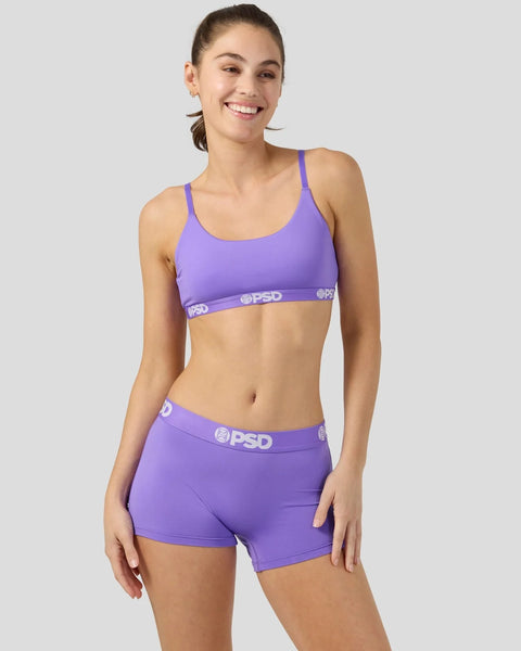 Woman wearing purple sports bra and shorts with PSD waistband detail.