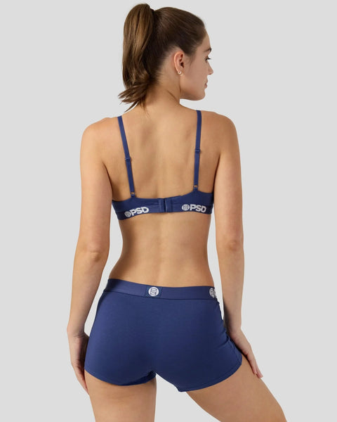 Woman wearing navy bra and shorts set with PSD branding, shown from back view.