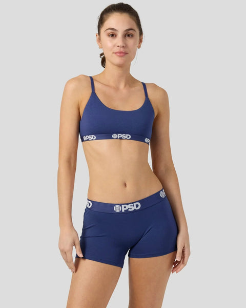 Woman wearing navy bralette and shorts set with white PSD waistband branding.