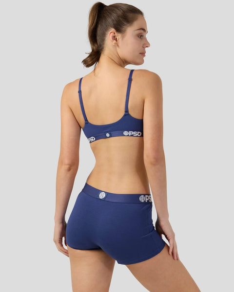 Woman wearing navy blue bra and shorts set with branded waistband, shown from back.