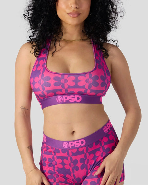 Woman wearing hot pink and purple floral print sports bra and matching shorts with PSD branding.