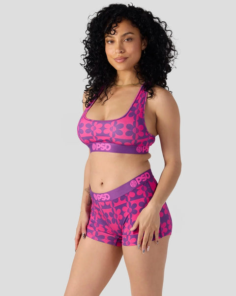 Woman wearing magenta and purple patterned sports bra and matching shorts with PSD branding.