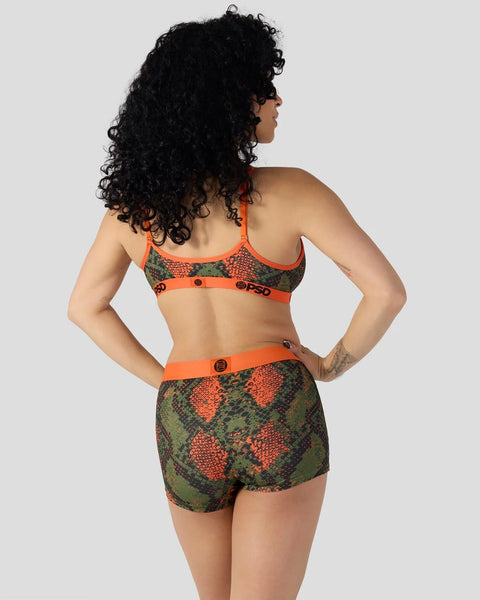 Woman wearing orange and green snake-scale patterned sports bra and matching shorts with orange trim and logo details.