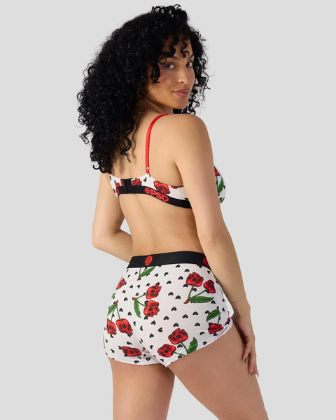 Woman wearing white cherry skull print bra and shorts with red straps and black trim, shown from back.