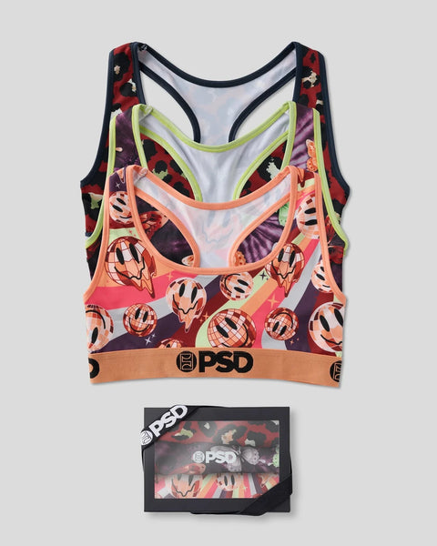 Three sports bras with patterned designs in red, purple, orange, and lime green with PSD branding and packaging box.