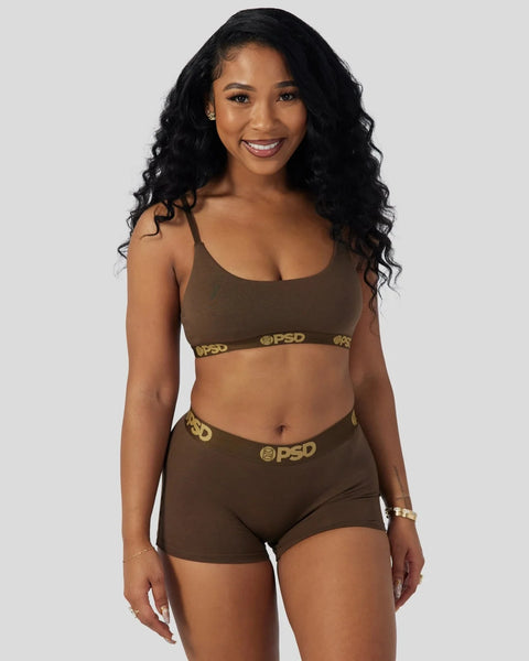 Woman wearing cocoa brown sports bra and matching shorts with gold PSD branding.