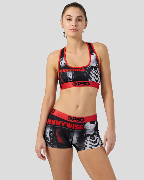 Woman wearing black and red Pennywise racerback sports bra and matching shorts with character graphics and PSD branding.