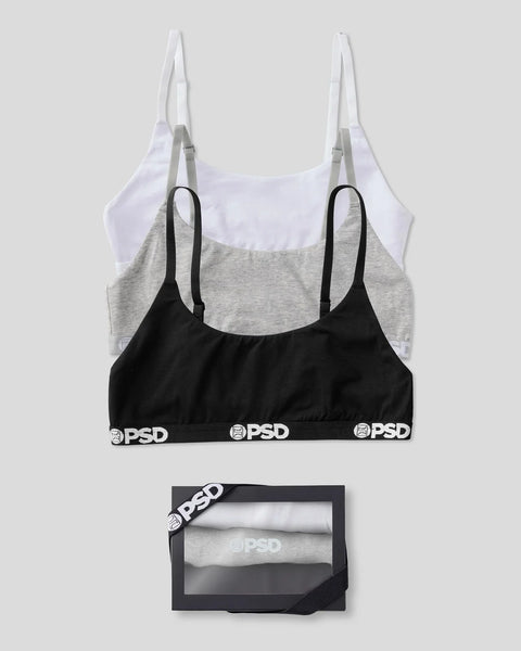 Three bralettes in white, light purple, and black with gray, displayed flat with packaging box below.