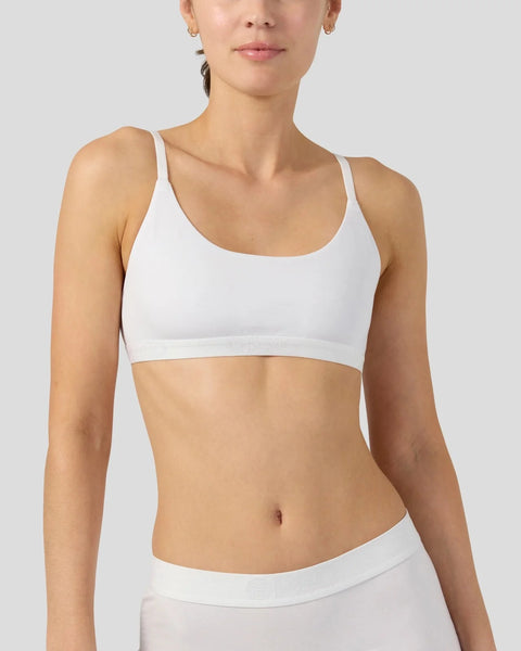 Woman wearing white racerback bra top with thin straps and scoop neckline.