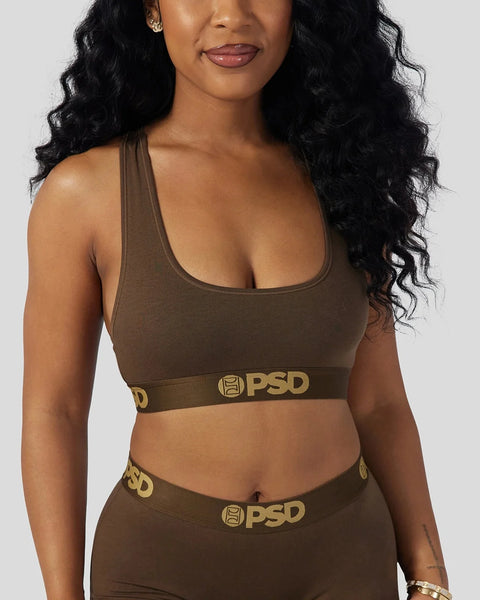 Woman wearing cocoa brown racerback sports bra with gold PSD waistband detail.