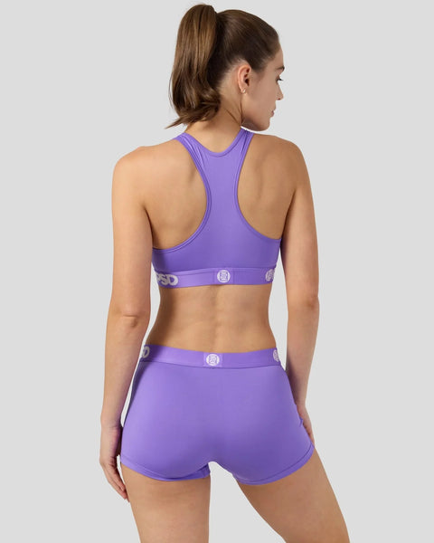 Purple sports bra and matching shorts set with branded waistband detail, shown on model from back view.